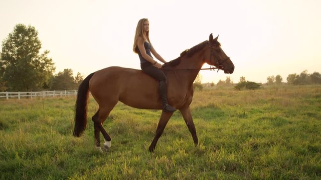 SLOW MOTION: Beautiful cheerful girl bareback riding mighty brown horse