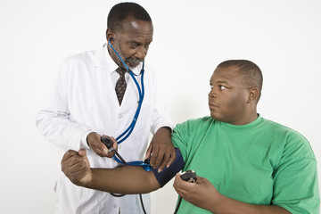 An African American doctor checking blood pressure of an obese patient in clinic