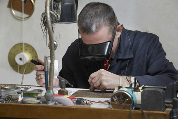 Middle aged repairman working on an old clock in workshop