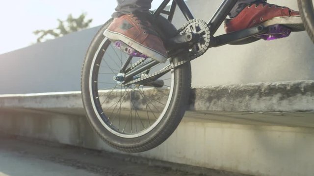SLOW MOTION CLOSEUP: Extreme bmx biker jumping on bench and doing peg grid trick