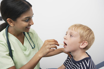 Female doctor examining preadolescent patient throat in the clinic