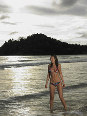 Obraz premium Smiling young woman in bikini looking away at the beach
