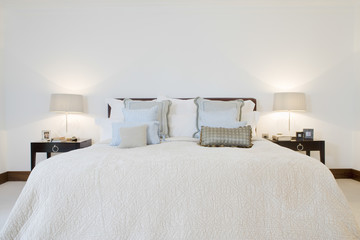 View of lit lamps by tidy bed