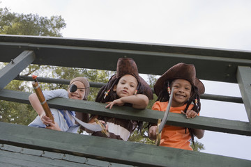 Low angle view of three kids in costumes looking through wooden railings