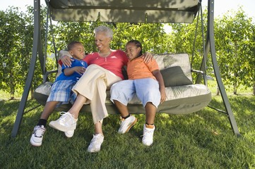 Happy African American senior woman with grandchildren sitting on swing chair