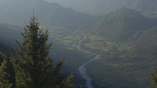 AERIAL: Mountain river running through beautiful green valley in sunny evening