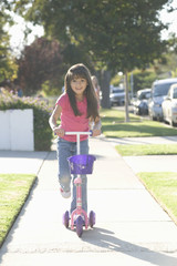 Full length portrait of a smiling young girl on scooter