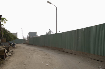 Fototapeta na wymiar Dirt Road Along Enclosed Corrugated Steel Fence
