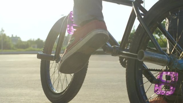 SLOW MOTION CLOSE UP: Bmx biker placing his foot on bike pedal and drives away