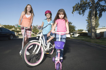 Full length portrait of children with scooters and bicycle