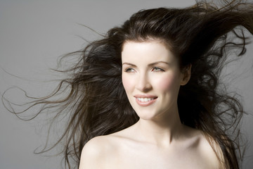 Closeup portrait of a beautiful woman with long hair against gray background