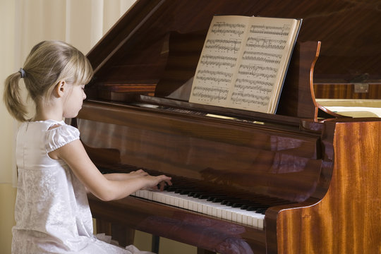 Side view of a young girl playing the piano