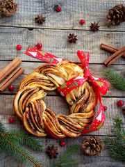 Cinnamon cocoa brown sugar wreath buns. Sweet Homemade christmas baking. Roll bread, spices, decoration on wooden background. New Year and Xmas card. Selective focus. Top view.
