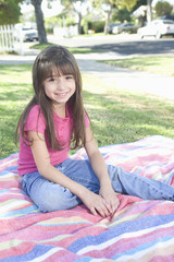 Portrait of a cute smiling girl sitting on picnic blanket