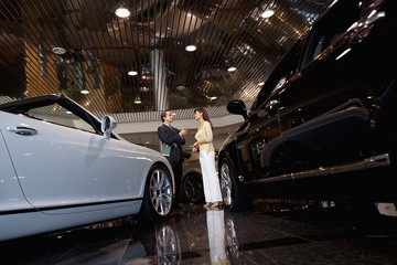 Salesman talking to woman in automobile showroom
