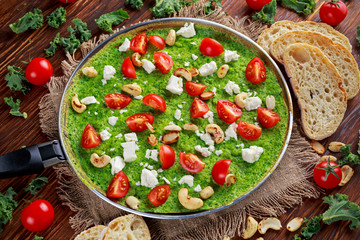 Vegetable Green Omelette with tomatoes, kale, greek cheese, olives, nuts, toast on wooden background. concept healthy food