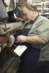 Obraz premium Side view of a male shoemaker at work in traditional workshop