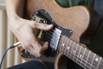 Fototapeta premium Closeup of a young man strumming chord on guitar