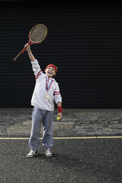 Full length of an excited young male winner raising tennis racket