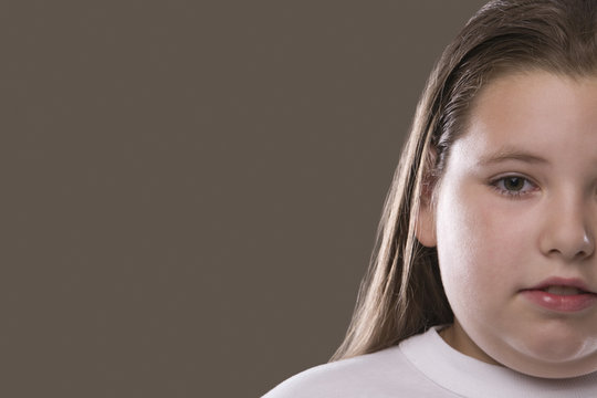 Closeup of an overweight serious girl against gray background