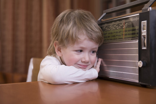 Closeup Of A Cute Boy Listening To Retro Radio At Home