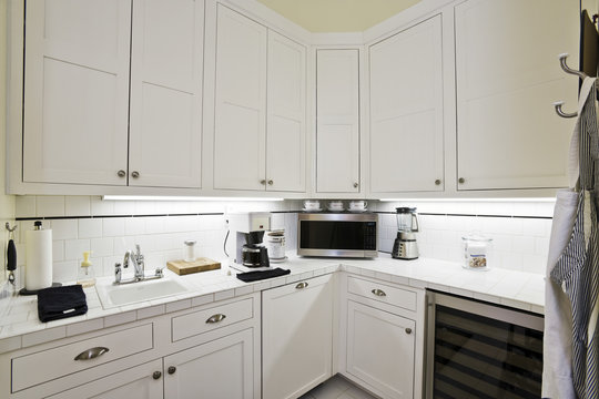Closeup of white cabinets with oven and coffee machine at the kitchen