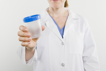 Midsection of a female nurse holding empty sample bottle isolated over white background
