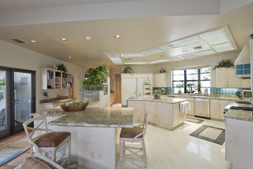 View of spacious kitchen with stools at island in house