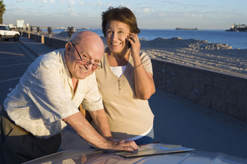 Portrait of happy senior couple with map on vacations
