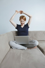 Victorious woman with hands raised in victory using a laptop at home