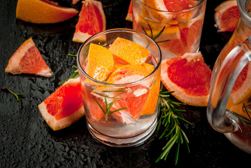 Refreshing summer detox cocktail of grapefruit and rosemary, with Ingredients, on black background, close view