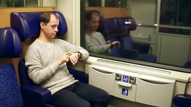 Man using his smartwatch in a train. Modern wearable device technology. 4K video