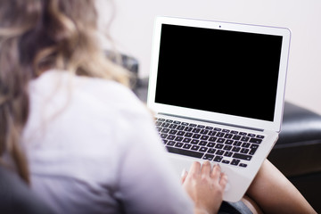 Woman sitting on a sofa using a laptop at home.