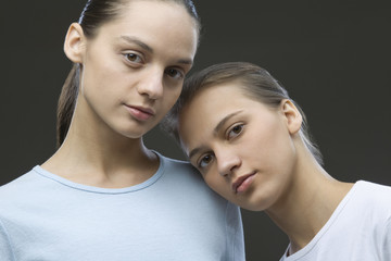 Closeup portrait of two contemplative sisters against black background