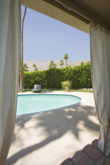 View of swimming pool through house window on a sunny day