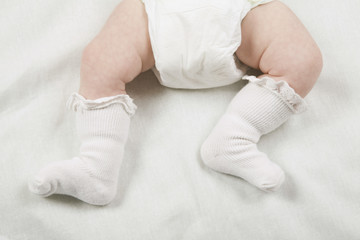 Closeup of a baby wearing diaper and socks in bed