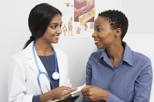 Happy female doctor giving prescription to patient in the clinic