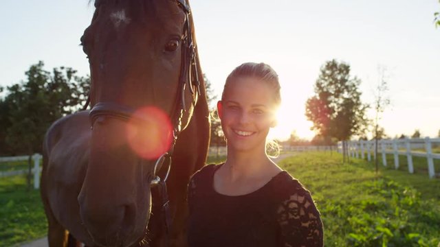 CLOSE UP: Portrait of strong brown horse and pretty happy girl on sunny day