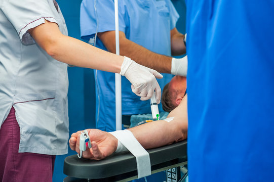 Close up anesthesiologist inserts the syringe making anesthesia to a patient