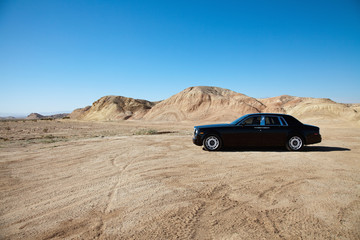 Luxury car parked on unpaved road near mountains