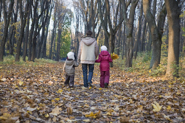 Fototapeta premium Full length rear view of mother and children walking in the park