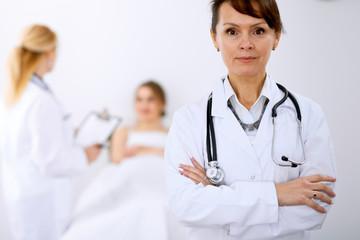 Fototapeta premium Female doctor smiling on the background with patient and his doctor