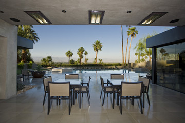 Outdoor tables on patio against swimming pool and sky