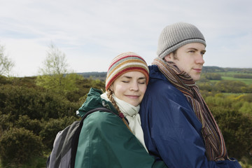 Young hiking couple embracing in field