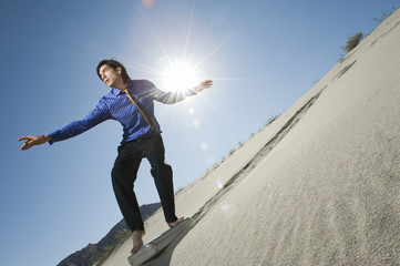 Young businessman surfing downhill on briefcase in the desert