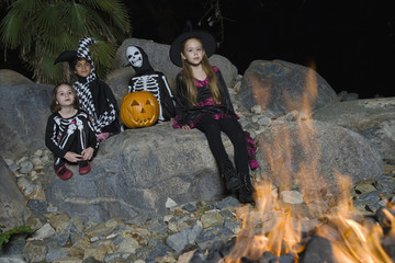 Four multiethnic friends dressed in Halloween costumes at campfire