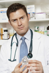 Portrait of a male doctor holding drug bottle in the clinic