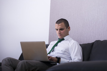 Businessman with laptop. Cheerful young businessman typing  on laptop.