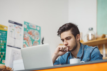 Young serious man with beard working on laptop