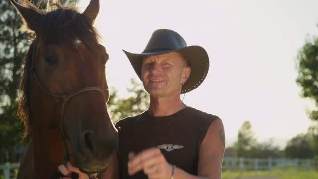 CLOSE UP: Portrait Of Cheerful Senior Cowboy Saying Hello And Touching His Hat